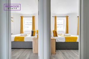 two beds in a room with yellow and white at Well-Equipped Serviced Apartments in Aldershot Town Centre, Free WiFi By Redwood Stays in Aldershot