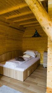 Bett in einem Holzzimmer im Dachgeschoss in der Unterkunft Rosa&Vera in Ucea de Sus