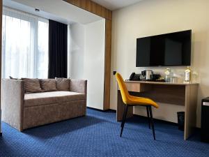 a hotel room with a couch and a television at Optima Collection Kamianske in Kamianske
