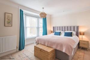a bedroom with a large bed with blue curtains at Prince's Cottage in Deal