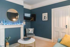 a living room with blue walls and a mirror at Prince's Cottage in Deal