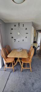 einen Tisch mit Stühlen und eine Uhr an der Wand in der Unterkunft Seaside View Holiday Home in Aberystwyth