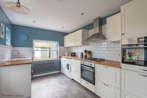 a kitchen with white appliances and blue walls at Prince's Cottage in Deal