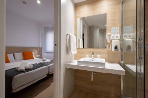 a bathroom with a sink and a bed in a room at Hostal Sans in Barcelona