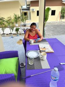 una mujer sentada en una mesa con un plato de comida en Vergers de Nil les roses, 