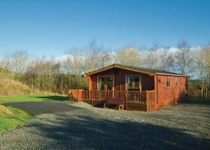 una baita di tronchi con portico e terrazza. di Nunland Hillside Lodges a Holywood