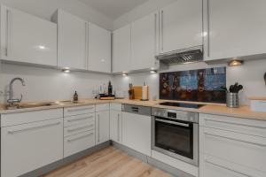 una cocina con armarios blancos y electrodomésticos de acero inoxidable en LoC - Oldenburg Altstadtlage, en Oldenburg