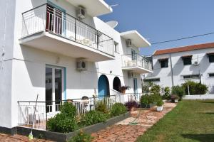 a white building with balconies and a yard at Kokkinia Gardens in Kavos