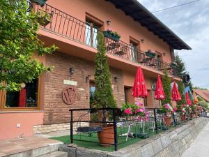 a building with tables and red umbrellas in front of it at Silver Bike Motel in Velden am Wörthersee