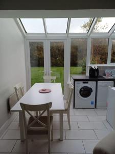 a kitchen with a white table and chairs and a window at Clifden Glen Cottage in Clifden +8 photos