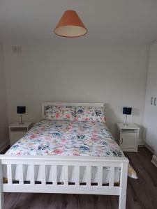 a white bed in a bedroom with two night stands at Clifden Glen Cottage in Clifden