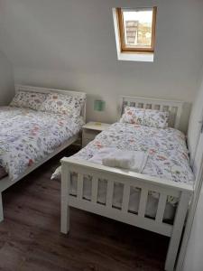 a bedroom with two beds and a window at Clifden Glen Cottage in Clifden