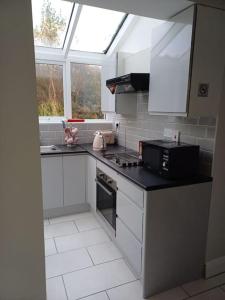 a kitchen with white cabinets and a black counter top at Clifden Glen Cottage in Clifden