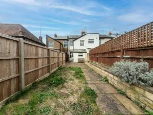 a fence in a yard with houses in the background at Charming Period Home near Surbiton with Garden in London