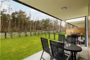 een patio met een tafel en stoelen en een tuin bij Modern Apartment With Private Garden Międzywodzie by Renters Prestige in Międzywodzie
