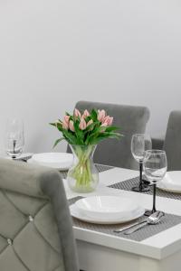 uma mesa de jantar com um vaso de flores cor-de-rosa em Modern Apartment With Private Garden Międzywodzie by Renters Prestige em Międzywodzie