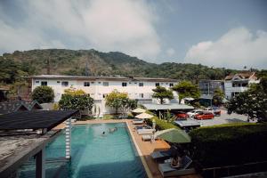 a hotel with a swimming pool in front of a building at The Melody Phuket - SHA Extra Plus in Kata Beach