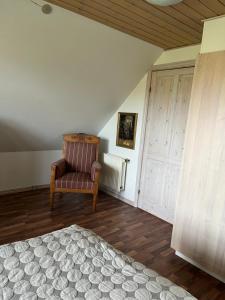 a bedroom with a bed and a chair and a door at Kallerup Hgård in Thisted