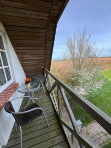 een houten veranda met een tafel en stoelen op een balkon bij Kallerup Hgård in Thisted