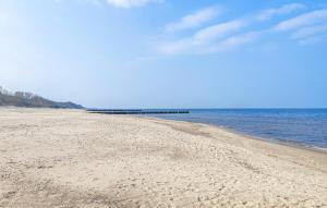 a sandy beach with a pier in the water at Cozy Home In Sarbinowo With Kitchen in Sarbinowo