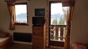 una camera da letto con TV e balcone con vista sulle montagne di Studio Bettex Pierre Platte a Saint-Gervais-les-Bains