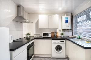 a kitchen with white cabinets and a washer and dryer at 4Bedrooms-Free Parking-6 Beds in Manchester