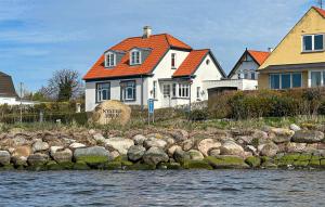 a white house with an orange roof next to the water at Beautiful Home In Nysted With House Sea View in Nysted