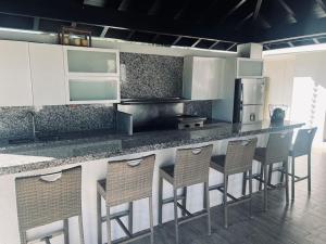 a kitchen with a counter with chairs and a refrigerator at Hacienda Ortiz: Luxury Space. in Matanzas