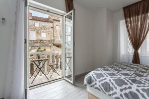 a bedroom with a bed and a view of a balcony at Riva Apartments Villa Thalia - Milna, Brač in Milna