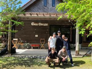 霧島市にあるゲストハウス Coco Garageの山小屋の前に立つ集団