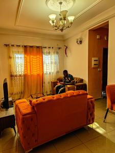 a man sitting on a couch in a living room at Résidence D in Bafoussam