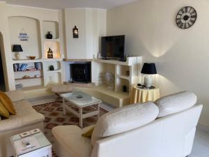 uma sala de estar com um sofá branco e uma televisão em LeComer em Carvoeiro
