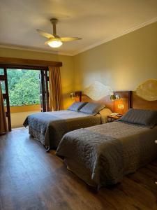 Cette chambre comprend 2 lits et une fenêtre. dans l'établissement Pousada Vovó Carolina, à Gramado