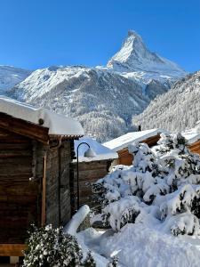 a snow covered cabin with a mountain in the background at Chalet Coral und Zermatter Stadel in Zermatt