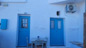 une chambre avec deux portes bleues et une table dans l'établissement Kamaraki Grande Aroniadika, à Cythère