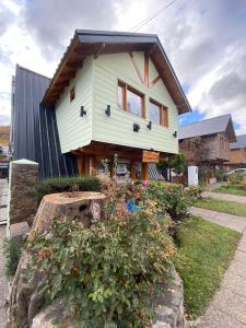 una casa pintada de verde con techo negro en Apart Hotel Ensueño en San Martín de los Andes