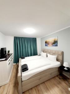 Schlafzimmer mit einem großen weißen Bett und grünen Vorhängen in der Unterkunft Pension Apostel in Wismar
