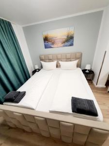 ein großes weißes Bett in einem Schlafzimmer mit grünen Vorhängen in der Unterkunft Pension Apostel in Wismar