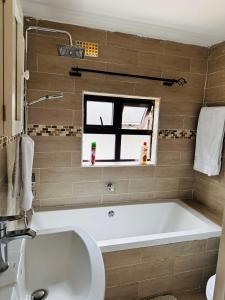 a bathroom with a tub and a sink and a window at Kaya Apartments 2 in Lusaka