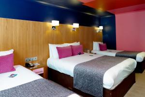 two beds in a hotel room with pink and blue walls at Skeffington Arms Hotel in Galway
