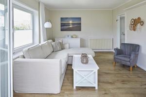 a living room with a white couch and a chair at Techts Sommerhaus in Timmendorfer Strand