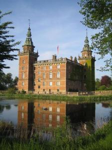 un gran edificio de ladrillo con dos torres junto a un cuerpo de agua en Luxury Tent with Restroom and shower, close to the Beach, en Ystad