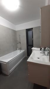 a white bathroom with a tub and a sink at AURORA suites in Ghiroda