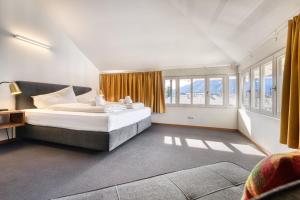 1 dormitorio con 1 cama grande y ventanas en Familienferienwohnung HEIMat en Bludenz