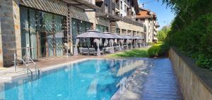- une piscine avec des parasols à côté d'un bâtiment dans l'établissement TERRA COMPLEX B4 - Private apartment - Golf, Skiing & SPA, à Bansko