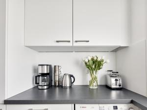 a kitchen with white cabinets and a vase of flowers at Techts Sommerhaus in Timmendorfer Strand
