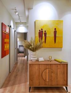 a hallway with a painting on the wall and a wooden cabinet at P Faliro Riviera Suite in Athens