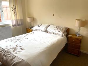 a bedroom with a white bed with pillows and a window at Caerhafod Nanternis in Llanllwchaiarn