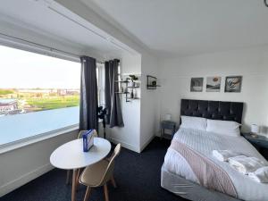 a bedroom with a bed and a table and a window at Harbour Flats in Skegness