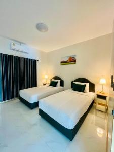 two beds in a hotel room with two lamps at Le Trang Boutique Airport in Trang